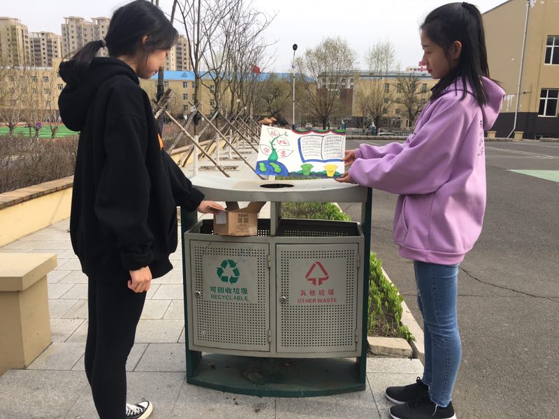 志愿者在校园垃圾桶旁指导同学垃圾分类.jpg